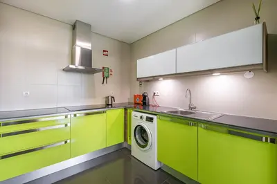 a kitchen with green cabinets and a washing machine at Sunrise House in Porto