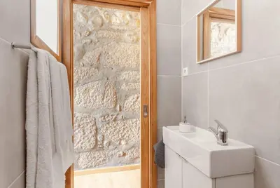 a bathroom with a sink and a stone wall at Goabio Apartment 3 Riverview in Porto