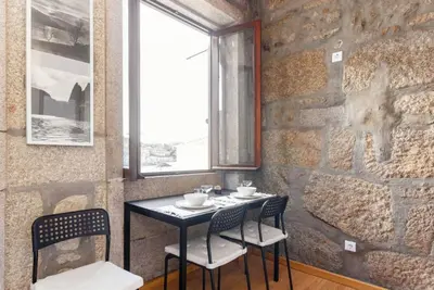a table and chairs in a room with a stone wall at Goabio Apartment 3 Riverview in Porto