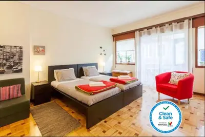 a bedroom with a large bed and a red chair at Cozy loft in downtown in Porto
