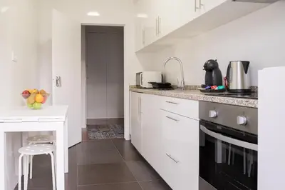 a kitchen with white cabinets and a black stove top oven at Simon Guest Apartments in Porto