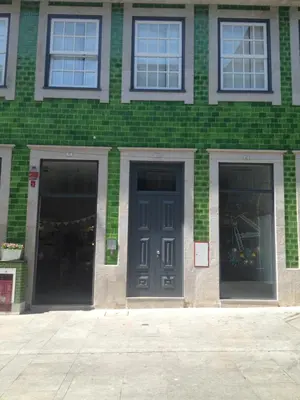 a green brick building with two blue doors at 45 Flores: Rua das Flores/S.Bento in Porto