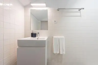 a white bathroom with a sink and a mirror at GuestReady - Mezzanine at the Bridge in Porto