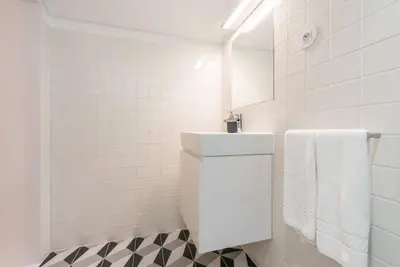 a white bathroom with a sink and white tiles at GuestReady - Mezzanine at the Bridge in Porto