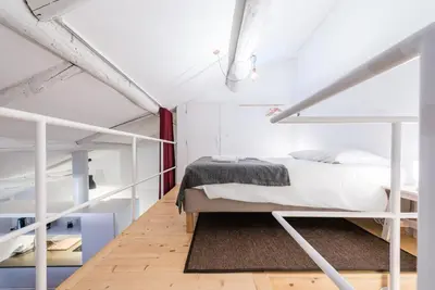 a bedroom with white bunk beds and a wooden floor at GuestReady - Mezzanine at the Bridge in Porto