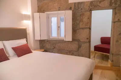 a bedroom with a white bed and a red chair at Ribeiredge Guest House in Porto