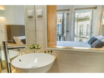 a bathroom with a sink and a mirror and a bed at Ribeiredge Guest House in Porto
