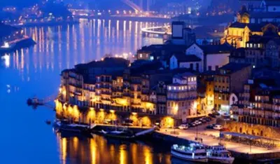 a city lit up at night with boats in the water at vitoria flat in Porto
