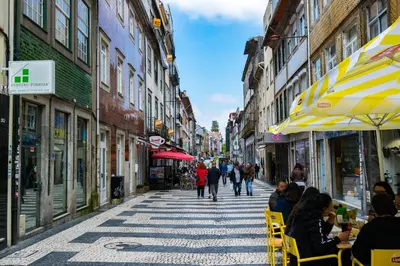 a city street with people sitting in chairs on the sidewalk at Merc Porto Central Place in Porto