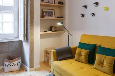 a living room with a yellow couch and bats on the wall at Old Stone Flats by Host Wise in Porto