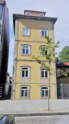 a yellow building with white windows on a street at Cozy Studio Apartment in Porto