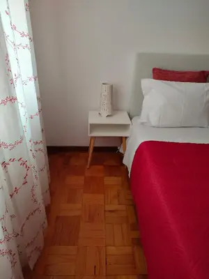 a bedroom with a bed with a red blanket and a table at Apartamento Boavista in Vila Nova de Gaia