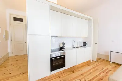 a kitchen with white cabinets and a wooden floor at Our Home City Flat in Porto