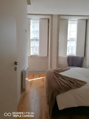 a bedroom with a bed and two windows at Chateau Flores in Porto