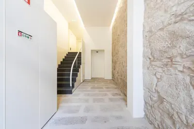 a hallway with stairs and a stone wall at Bright Downtown Apartment in Porto