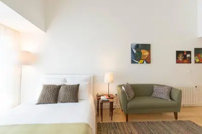 a bedroom with a bed and a green chair at Bright Downtown Apartment in Porto