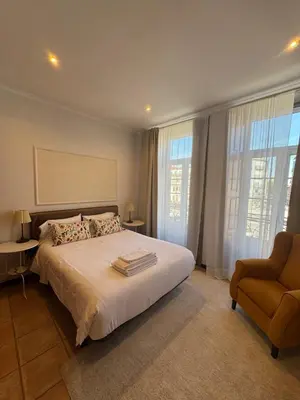 a bedroom with a bed and a chair and windows at Turra Residence in Porto