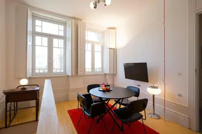 a living room with a table and chairs and a television at 14º Esquadra — Cais das Pedras Guest House in Porto