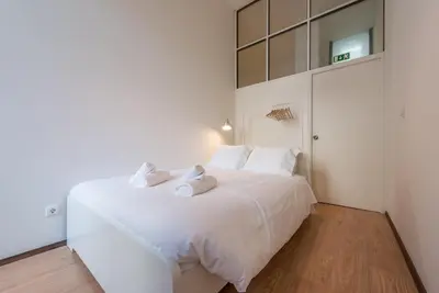 a white bedroom with a large white bed with white pillows at GuestReady - Clérigos Virtudes Apartments in Porto