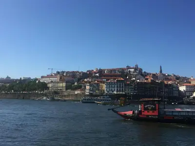 a boat on a river with a city in the background at PortoVivo Quental Apartamento in Porto