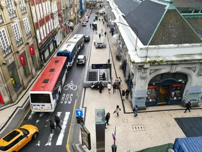 a busy city street with buses and cars and pedestrians at Pontocom Bolhão Apartment in Porto