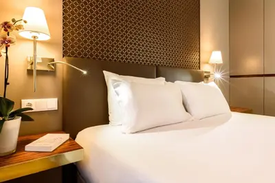 a hotel room with a bed with white pillows at Exe Almada Porto in Porto