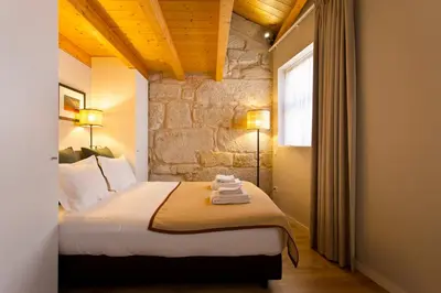 a bedroom with a large bed with a stone wall at RVA - Sao Joao Novo Apartments in Porto