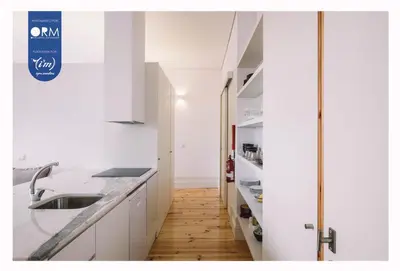 a kitchen with white cabinets and a wooden floor at ORM - Cativo Apartments in Porto