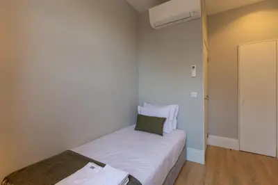 a small bedroom with two beds and a radiator at ORM - Bolhao Apartments in Porto