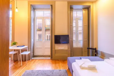 a room with two beds and a television and a table at ORM - Bolhao Apartments in Porto