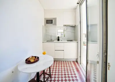 a small white kitchen with a table and a sink at Pause Apartments in Porto
