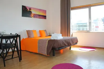 a bedroom with a bed with orange sheets and a table at Trindade Oporto Apartments Group in Porto