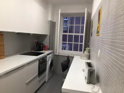 a white kitchen with a sink and a window at Ribeira Apartment in Porto