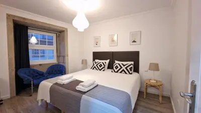 a bedroom with a large bed with two blue chairs at Merc Porto Ribeira's View in Porto