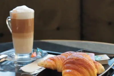 a tray with a cup of coffee and a croissant at Oporto Serviced Apartments - Alvares Cabral in Porto