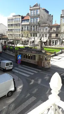 a train on a city street with cars and buildings at OPorto Histórico - Galerias in Porto