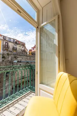 a balcony with a yellow chair and a window at Downtown Porto Mouzinho Studio Apts in Porto