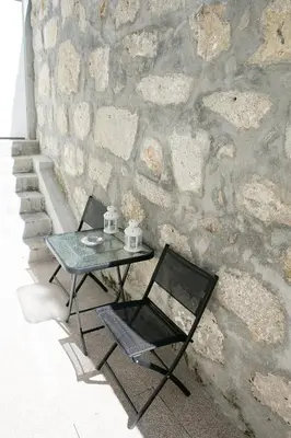 a table and a chair next to a stone wall at Covelo Apartment in Porto