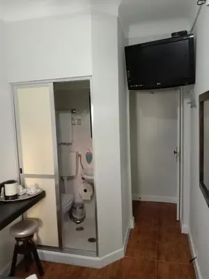 a bathroom with a toilet and a tv on the wall at Faria Guimares Porto Centro in Porto