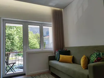a living room with a couch and two windows at Suite na baixa do Porto in Porto