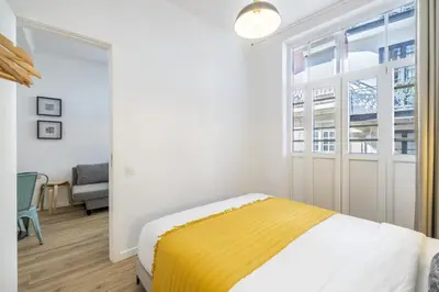 a white bedroom with a bed and a window at D&S - Loureiro 67 in Porto
