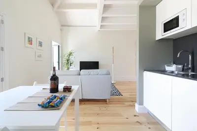 a white kitchen with a table with a bottle of wine at Msc Flats in Porto