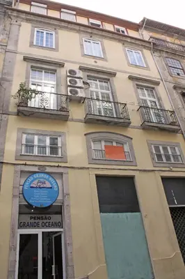 a tall building with windows and a sign on it at Grande Oceano Guest House in Porto