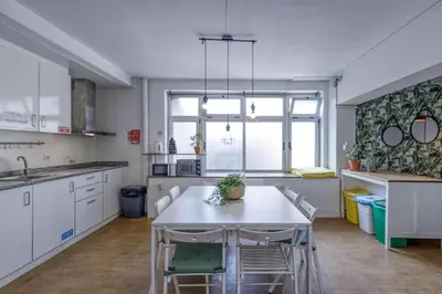 a kitchen with a white table and chairs in it at Travel & Live Hostel in Porto