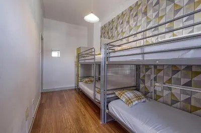 a room with three bunk beds and a hallway at Travel & Live Hostel in Porto