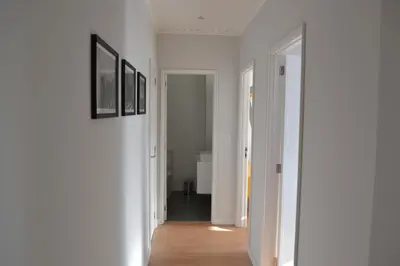 a hallway with white walls and wood floors and pictures at RockInn Porto in Vila Nova de Gaia