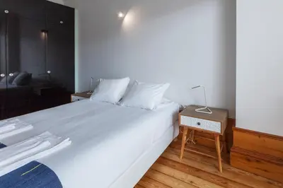a bedroom with a large white bed with a night stand at Go2oporto - Fontainhas Apartments in Porto