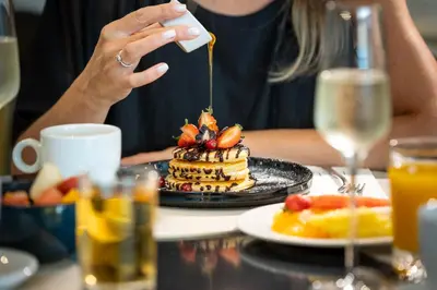 a woman is drizzling syrup onto a stack of pancakes at Hotel Cristal Porto in Porto