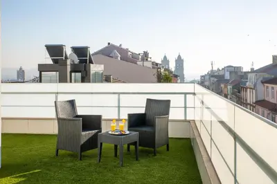 a balcony with three chairs and a table with drinks on it at Hotel Cristal Porto in Porto
