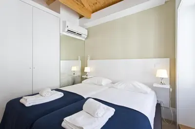 a white bedroom with two white towels on a bed at RVA - Clerigos Apartments in Porto